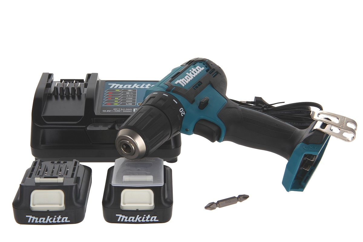 A compact Makita DF333DSAE cordless drill/driver in turquoise and black is positioned diagonally. Next to it are two black 12V batteries, a matching charger and a PH2 double-ended bit. All components are arranged against a white background.