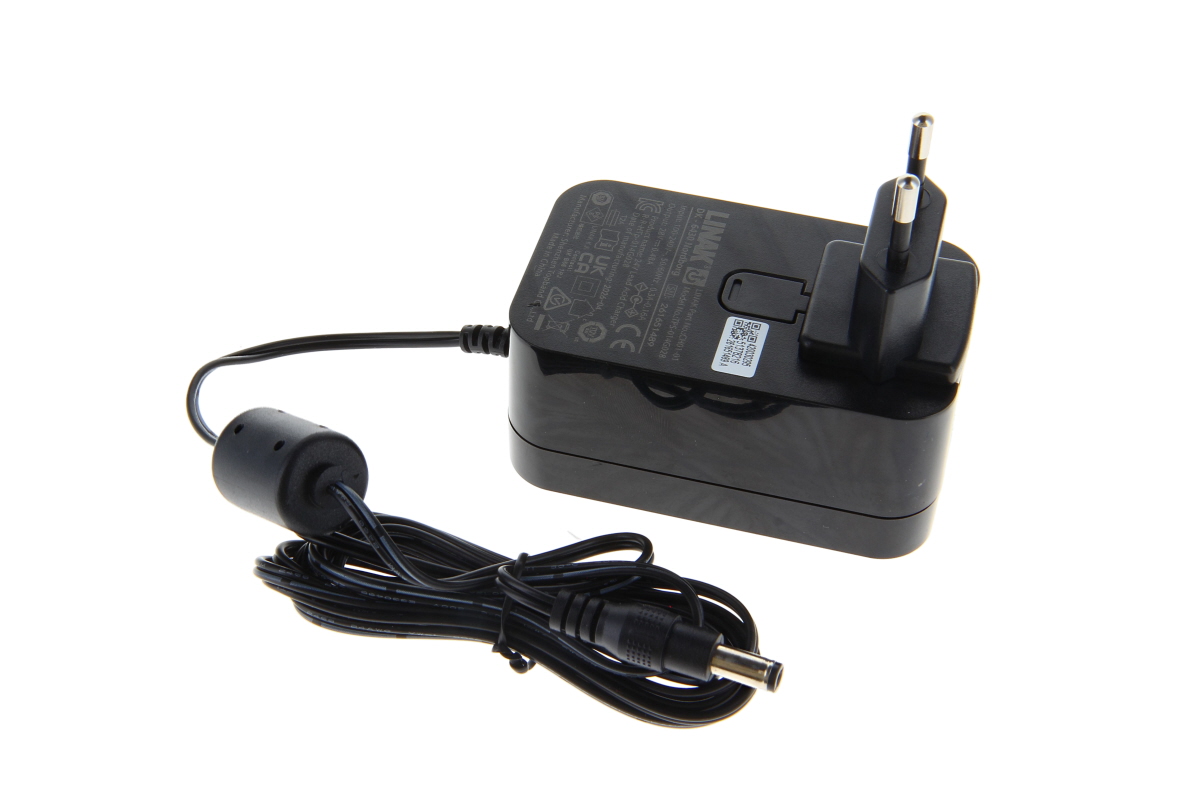 Schwarzes Linak Ladegerät CH01-01 mit EU-Stecker nach oben. Langes spiralförmiges Kabel mit Ferritkern und rundem DC-Stecker. Auf dem Gehäuse: technische Daten und QR-Code. Auf neutralweißem Hintergrund.