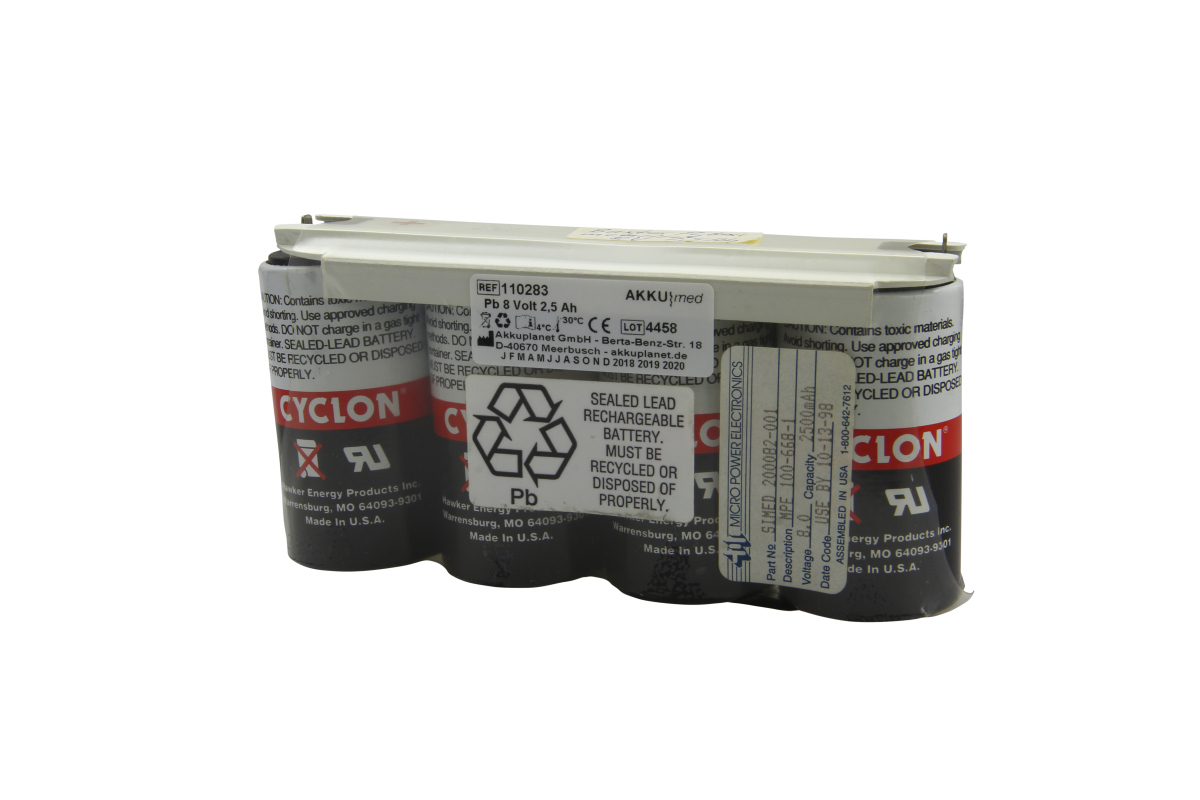 Horizontal battery pack containing four cylindrical black lead-acid cells and a red ‘CYCLON’ logo. A white frame holds them together at the top. White labels with information/warnings: ‘AKKU|med’, ‘8 Volt 2.5 Ah’, lead recycling symbol.